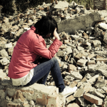 Woman holding her head in despair amid rubble