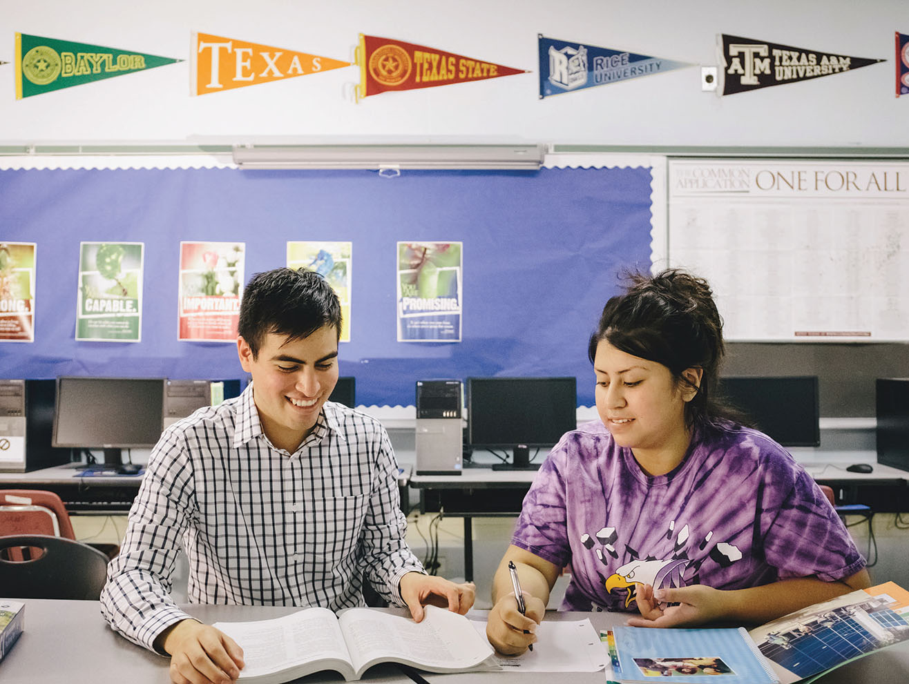 Two young people in a classroom looking at college materials