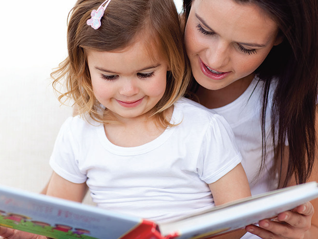 Mother reading a picture book to a preschool girl