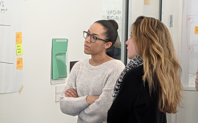 Three female students examining a white board