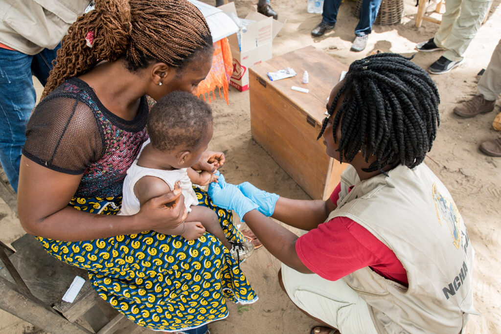 Community health worker delivers care to mother holding baby