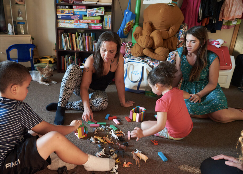 Two women playing on the floor with two children