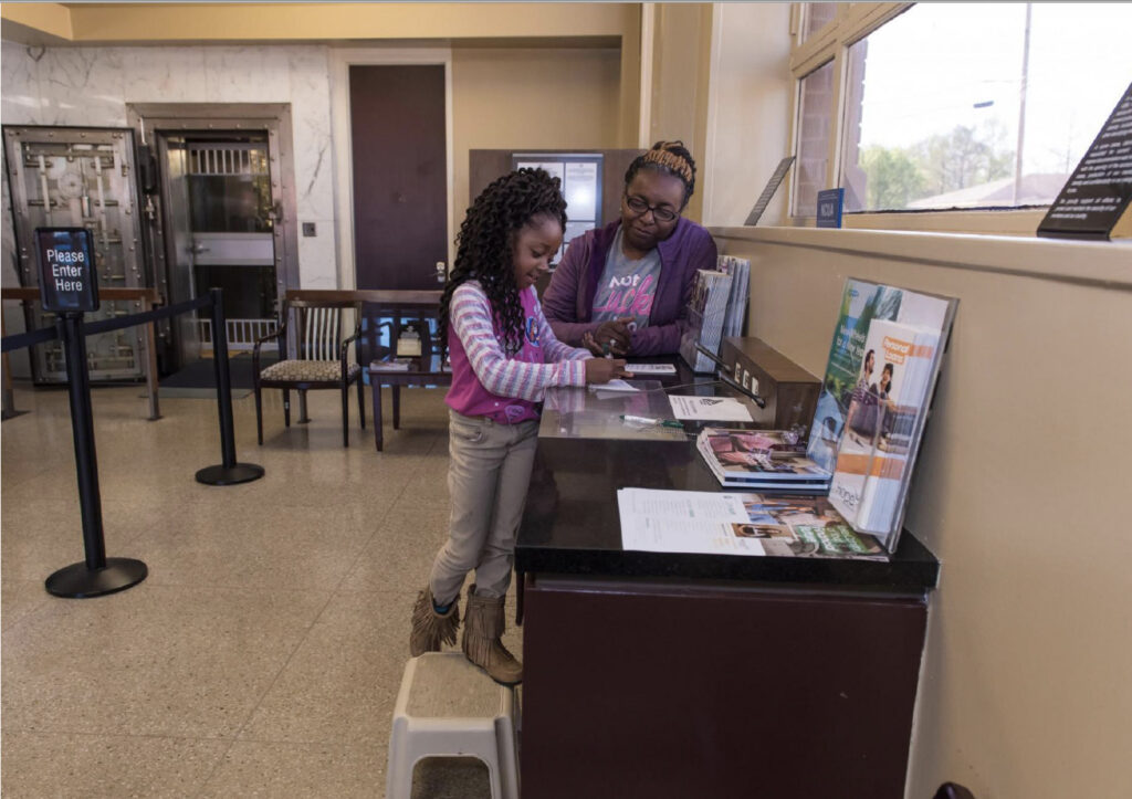 Woman helping a child fill out a bank slip