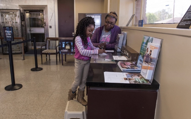 Woman helping a child fill out a bank slip