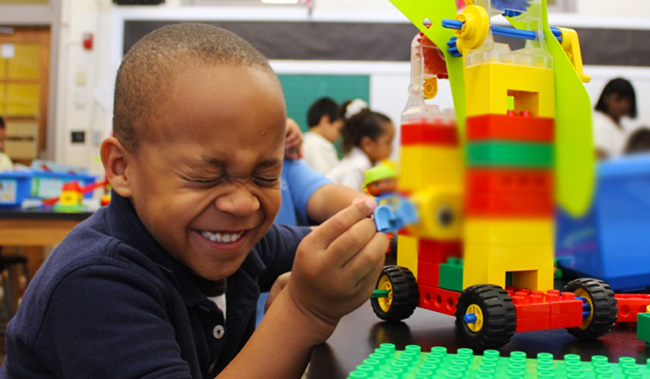 Little boy playing with Lego blocks in classroom