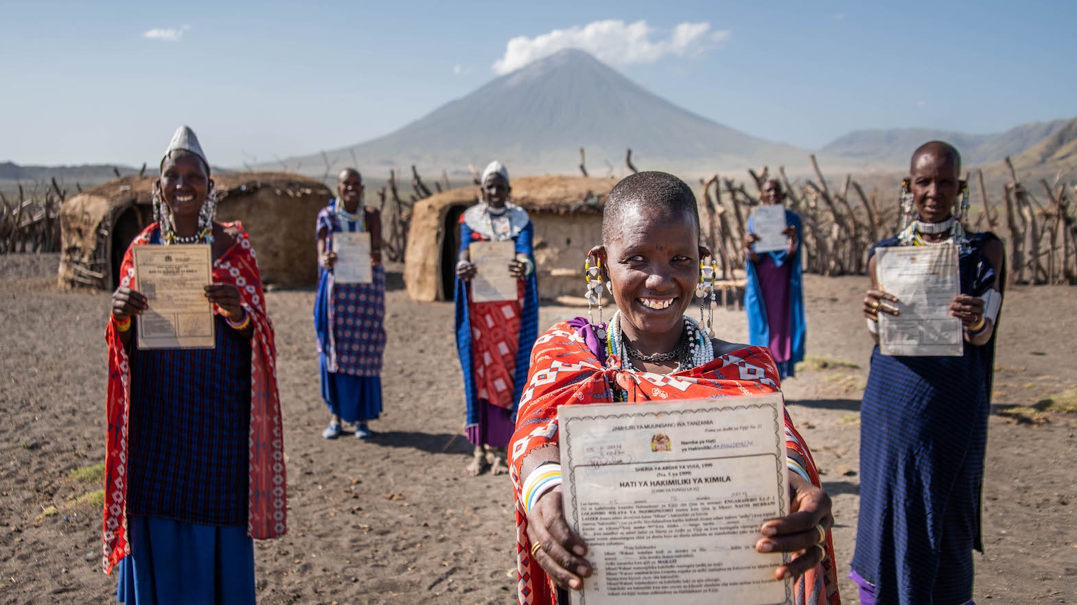 smiling Masai women holding diplomas in front of Mt. Kilimanjaro