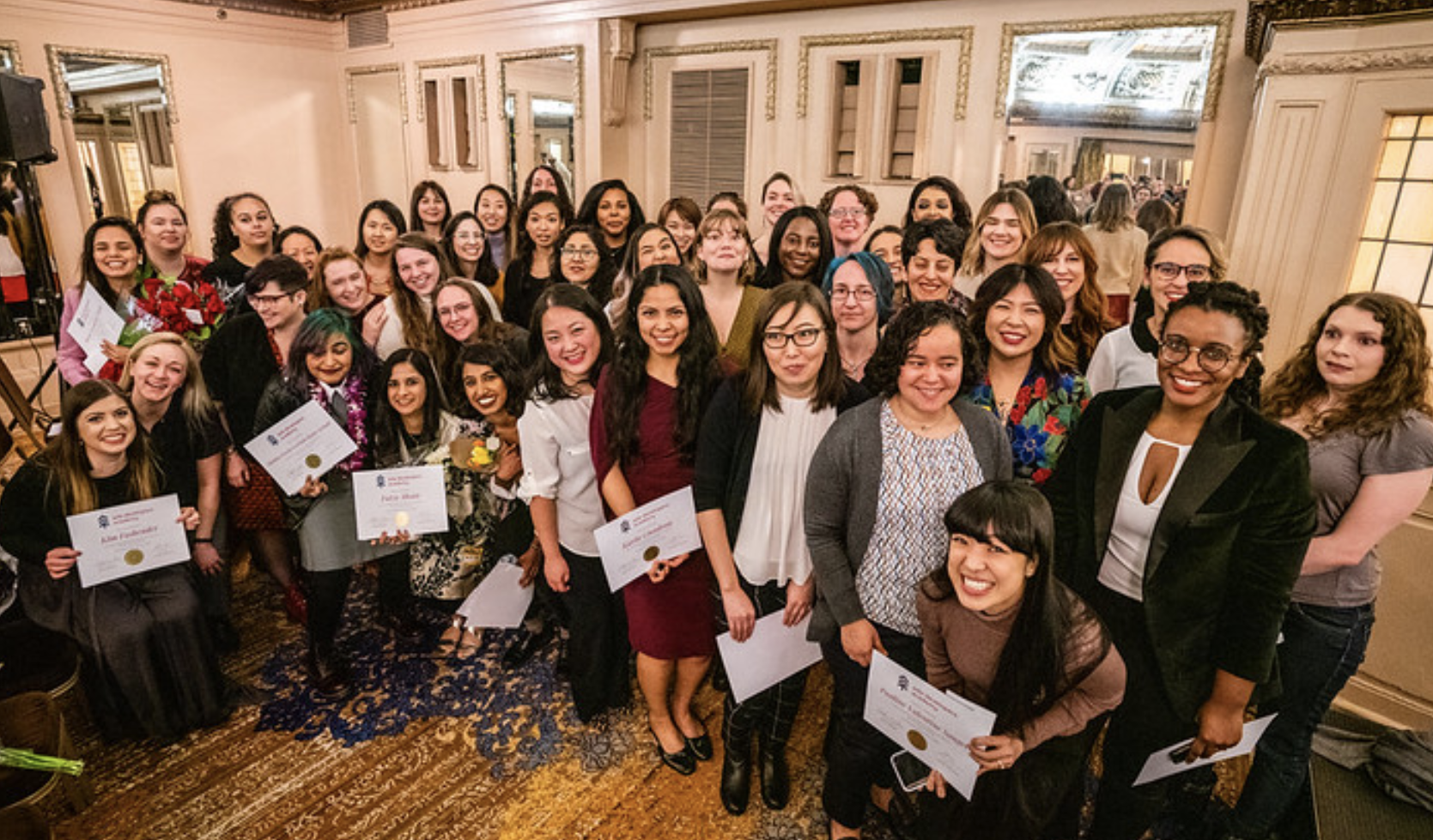 Large group of women in business dress holding diplomas