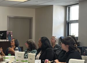 Kat Rosqueta sits next to Amy Schiller at a crowded table.