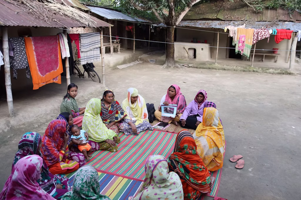 A community health worker sits with a group of young mothers